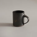 Black ceramic mug on a light gray background