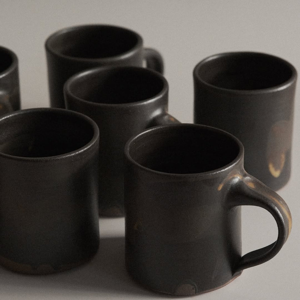 Set of black ceramic mugs on a neutral background