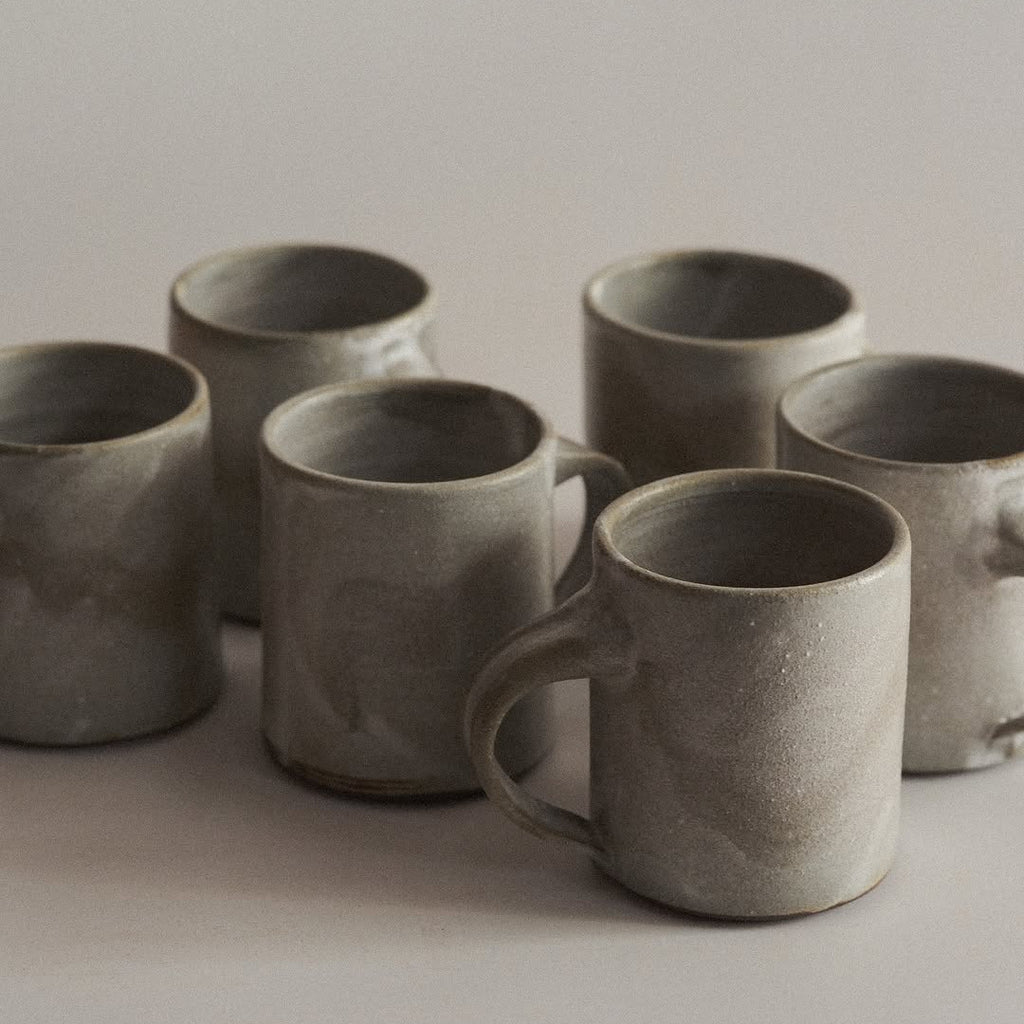 Set of six ceramic mugs on a neutral background