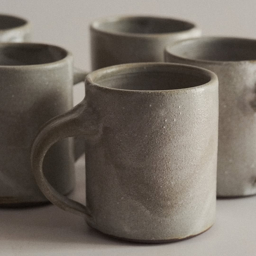 Set of gray ceramic mugs on a light background